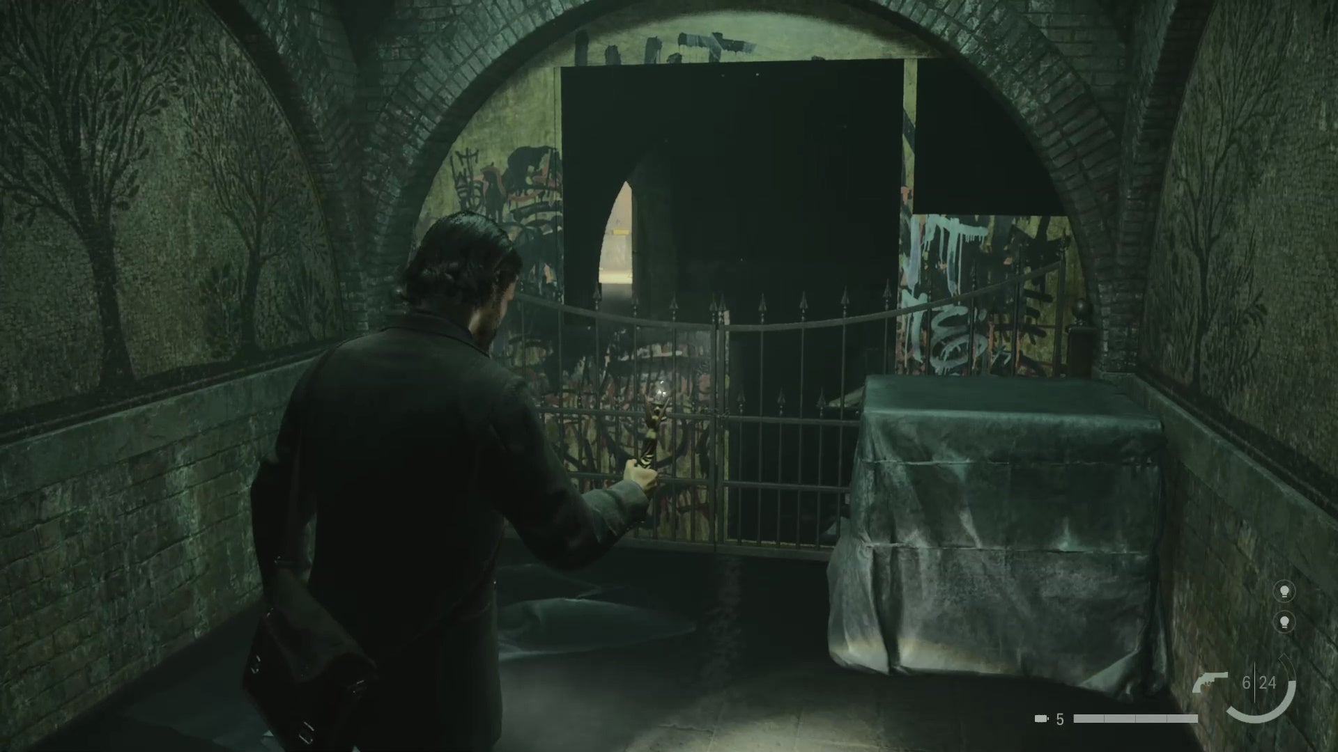 alan using the angel lamp on a light source near a dilapidated wall covered in graffiti with a gap in it, in a dark rundown train station tunnel