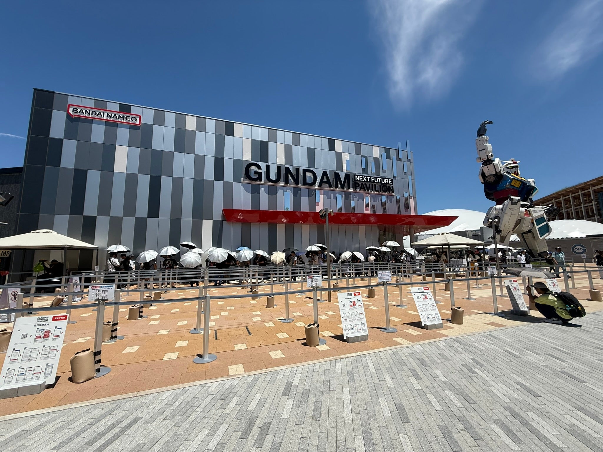 Photo from the World Expo 2025 in Osaka showing a building labelled GUNDAM with a giant Gundam statue outside, and queue of attendees