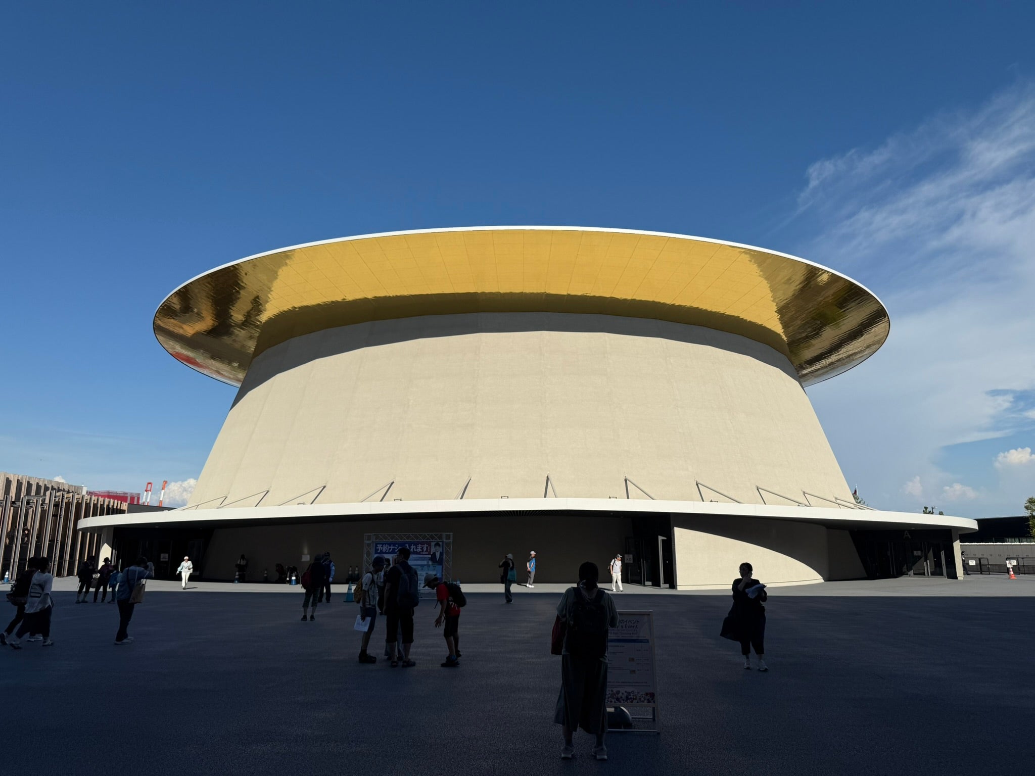 Photo from the World Expo 2025 in Osaka showing a futuristic, reflective gold cylindrical building