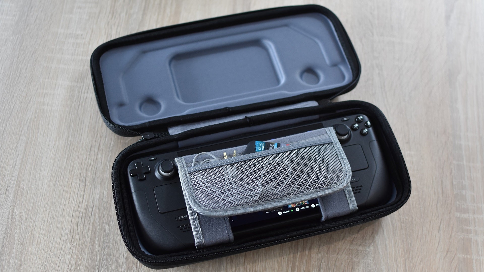 A Steam Deck inside the JSAUX Carrying Case. A headphone cable and several microSD cards are inserted into its folding storage pocket. - 6