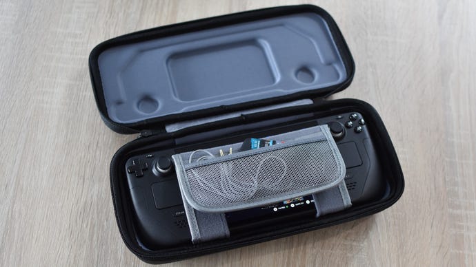 A Steam Deck inside the JSAUX Carrying Case. A headphone cable and several microSD cards are inserted into its folding storage pocket.