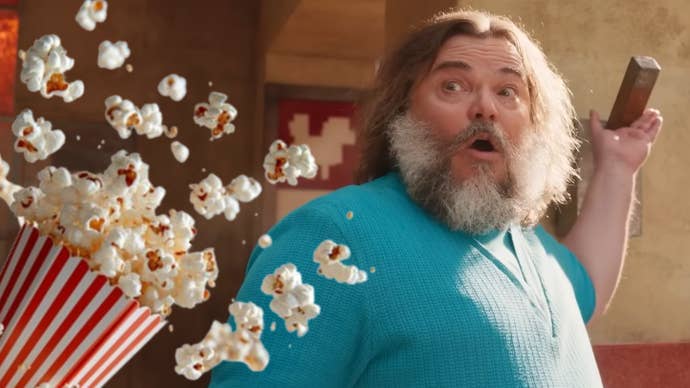 Jack Black as Steve in A Minecraft Movie looks shocked as a bucket of popcorn gets launched towards him