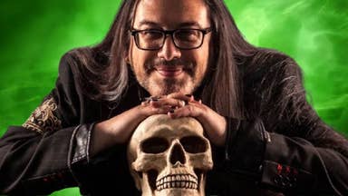 John Romero leans on a skull as he smiles at the camera. His image is laid over the top of a Microsoft green
