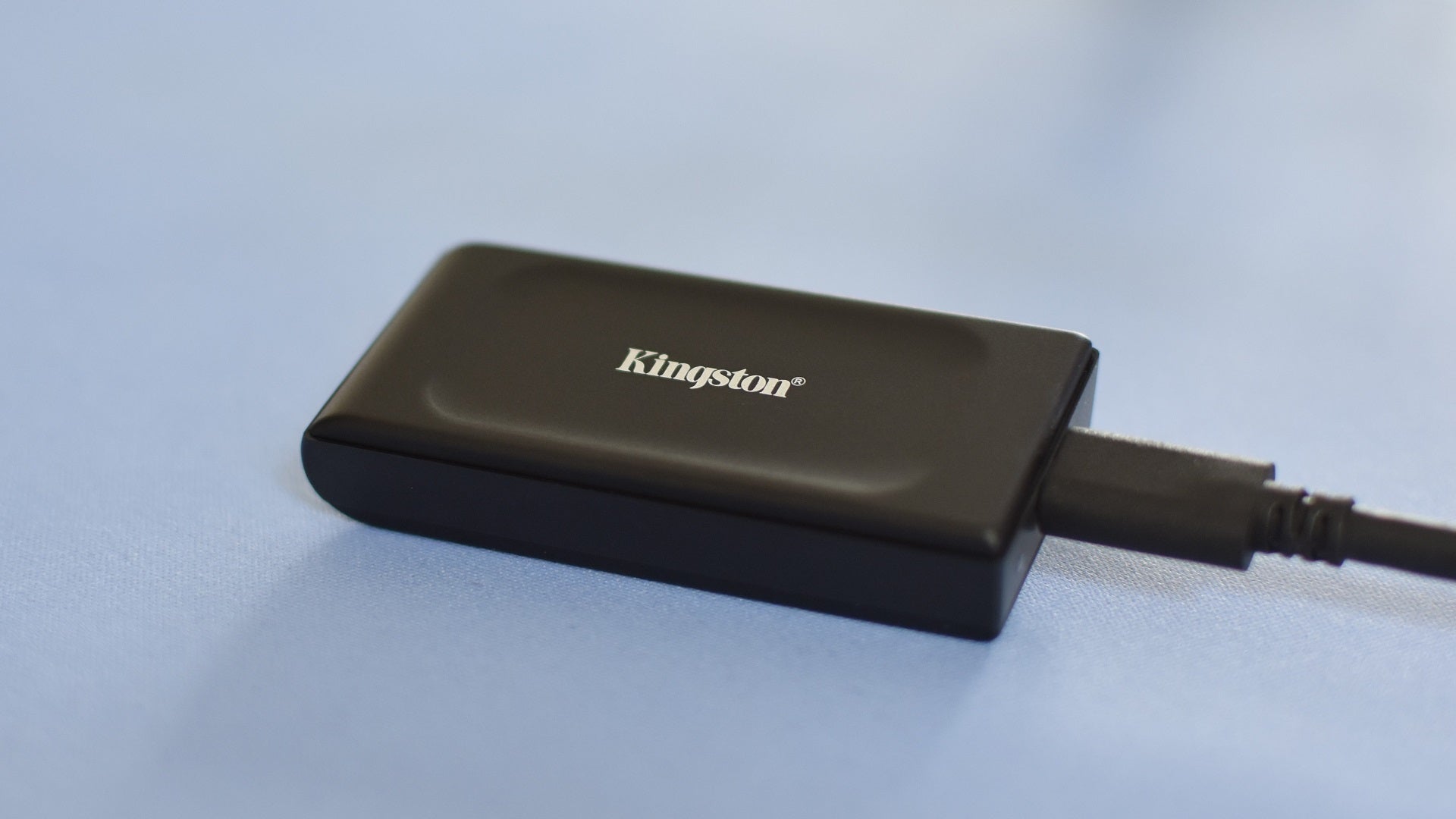The Kingston XS1000 SSD on a blue mat. - 13