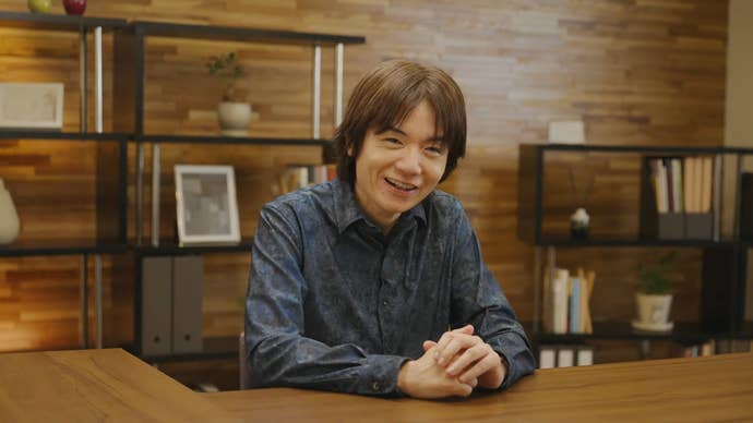 Masahiro Sakurai sat at a desk presenting the Kirby Air Riders Direct