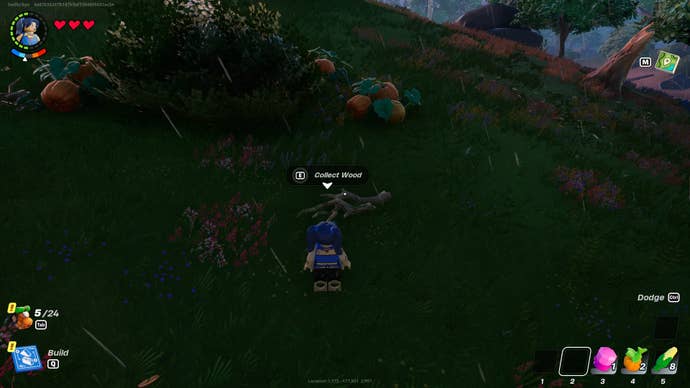 The player looks at picking up some wood from the floor, nearby a bush and some pumpkins in LEGO Fortnite