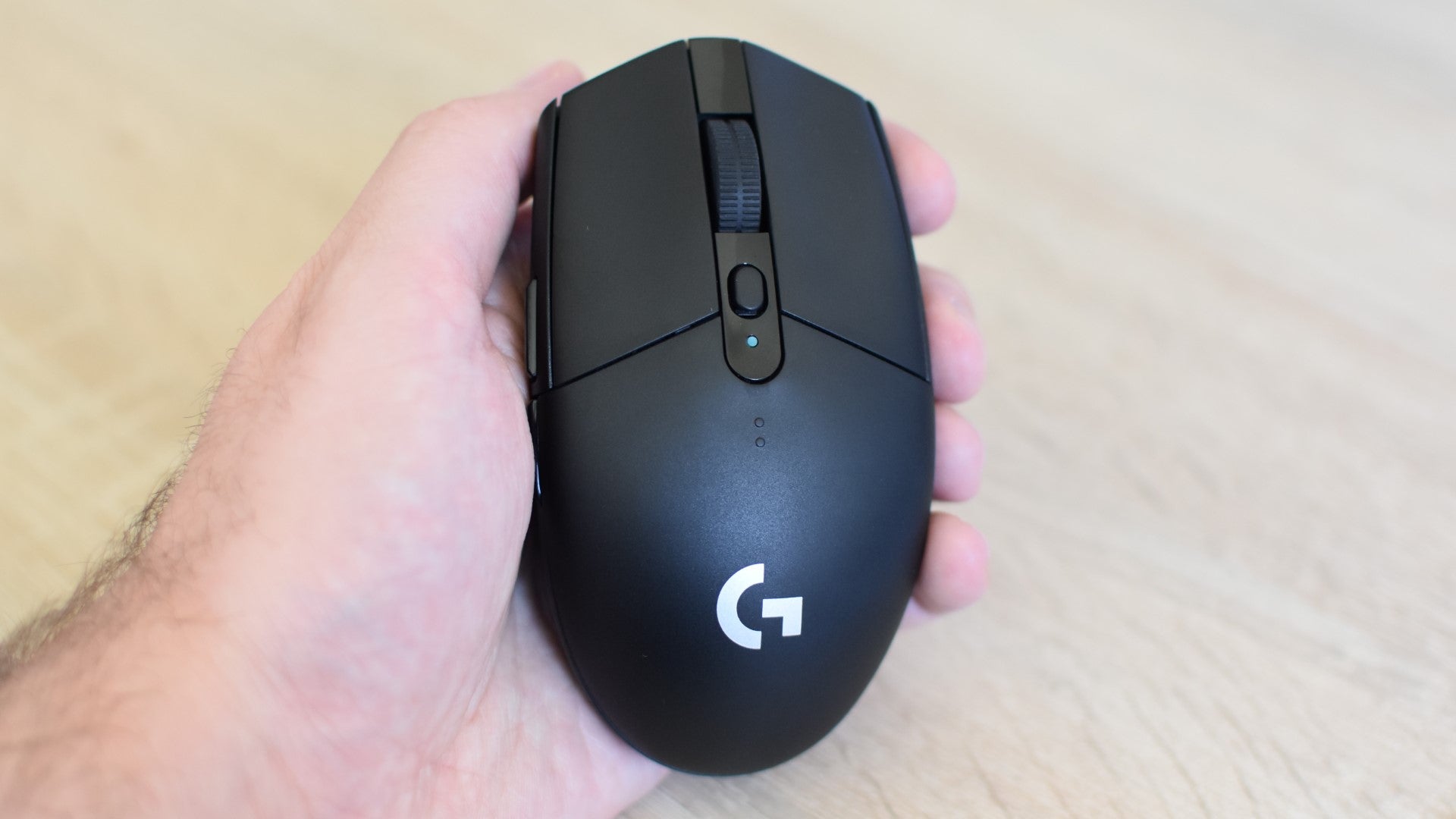 A Logitech G305 Lightspeed mouse being held in a hand. - 1