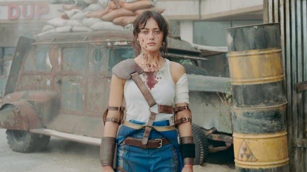Ella Purnell as Lucy in Amazon's Fallout adaptation. She is wearing a white tank top that is splattered with blood
