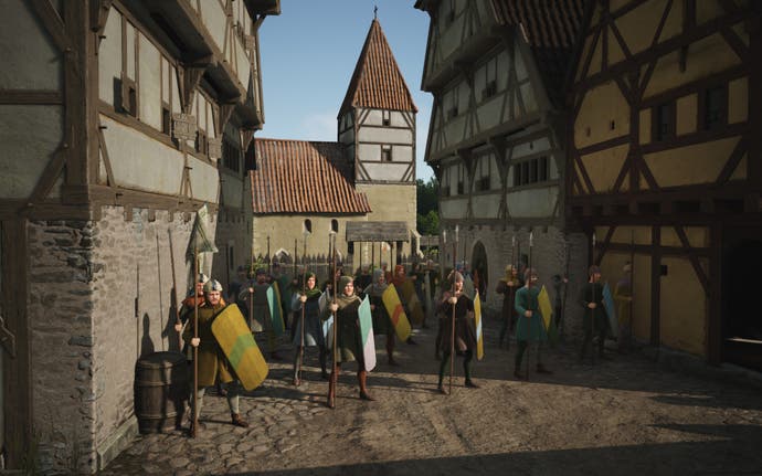 An army of soldiers stand guard between large houses in Manor Lords