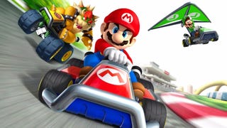 Mario Kart 7 promo image showing Mario front and centre in a red a blue kart. Bowser is coming up on his left (as you look at the pic) while Luigi soars through the air on the right with a green glider attached to his kart