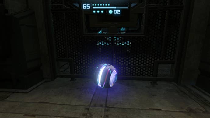 As the Morph Ball, Samus sits in front of a bombable barrier in Metroid Prime Remastered