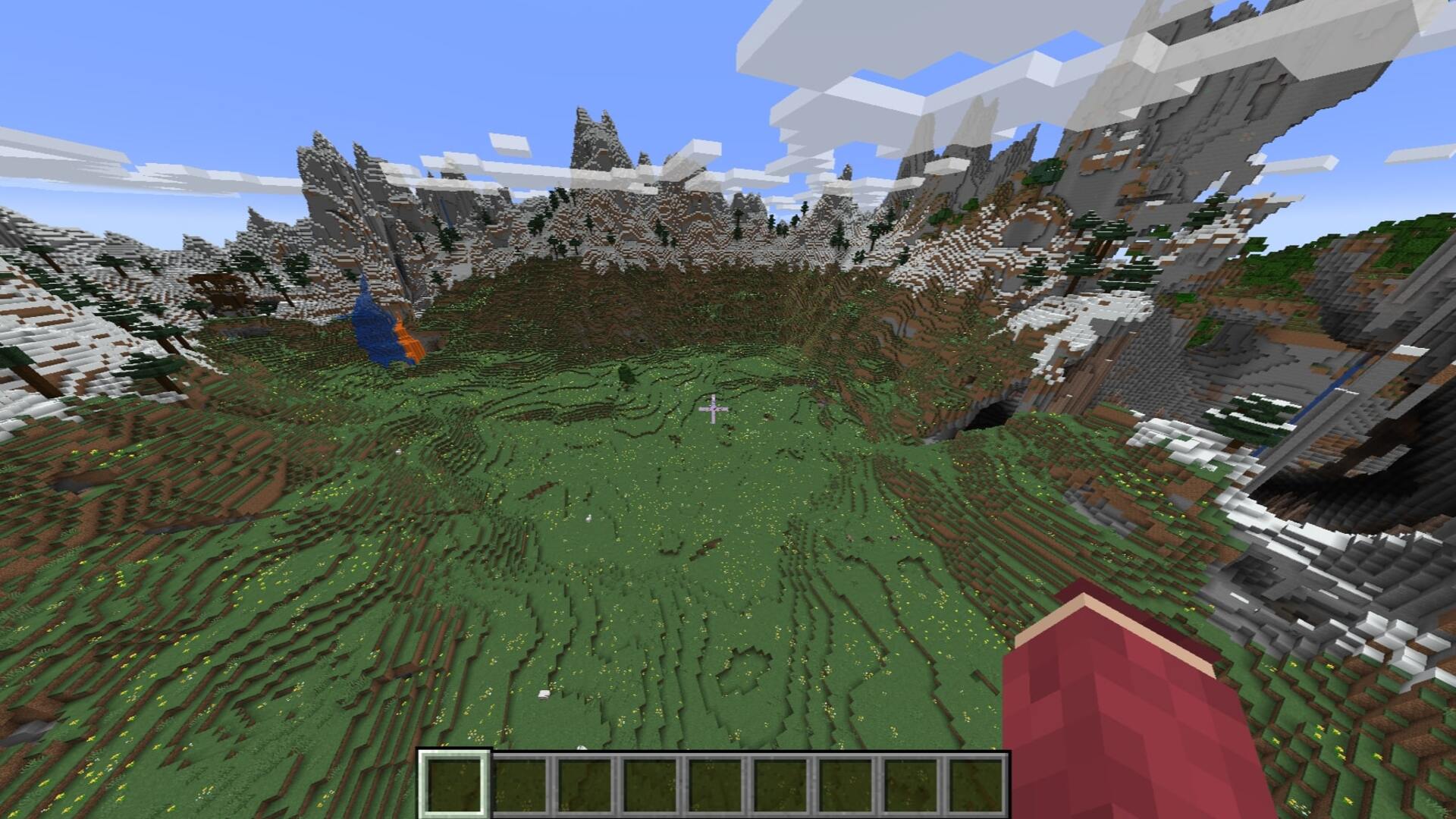 The player looks down at a large flat meadow surrounded by mountains and caves in Minecraft