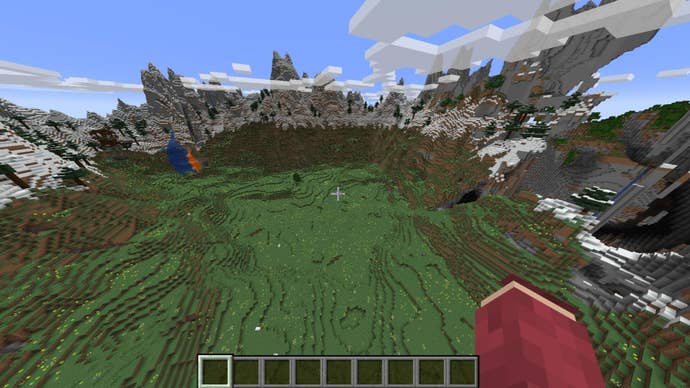 The player looks down at a large flat meadow surrounded by mountains and caves in Minecraft