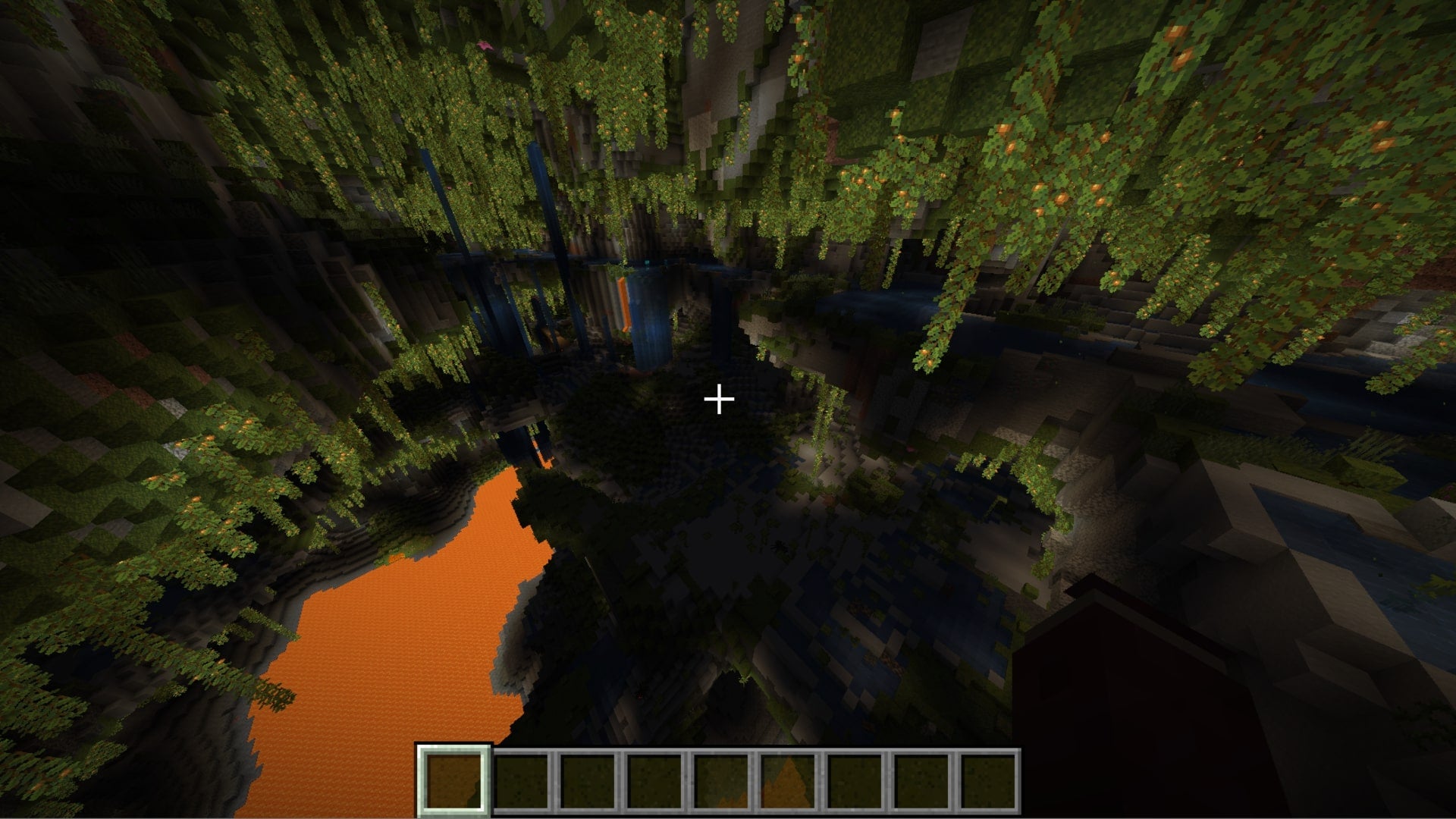 The player looks down at a huge lush cave system filled with lava in Minecraft