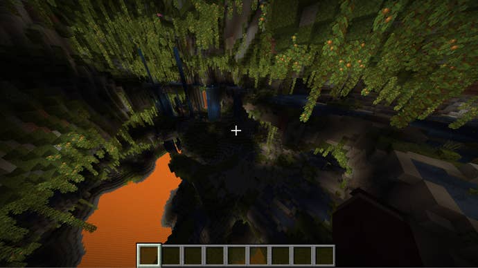 The player looks down at a huge lush cave system filled with lava in Minecraft