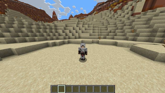 The player, wearing the Altair (Assassin’s Creed) skin, stands in a desert in Minecraft