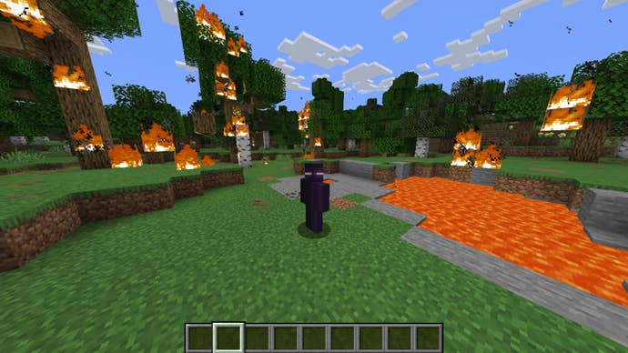 The player, wearing the Enderman skin, stands in a burning forest in Minecraft