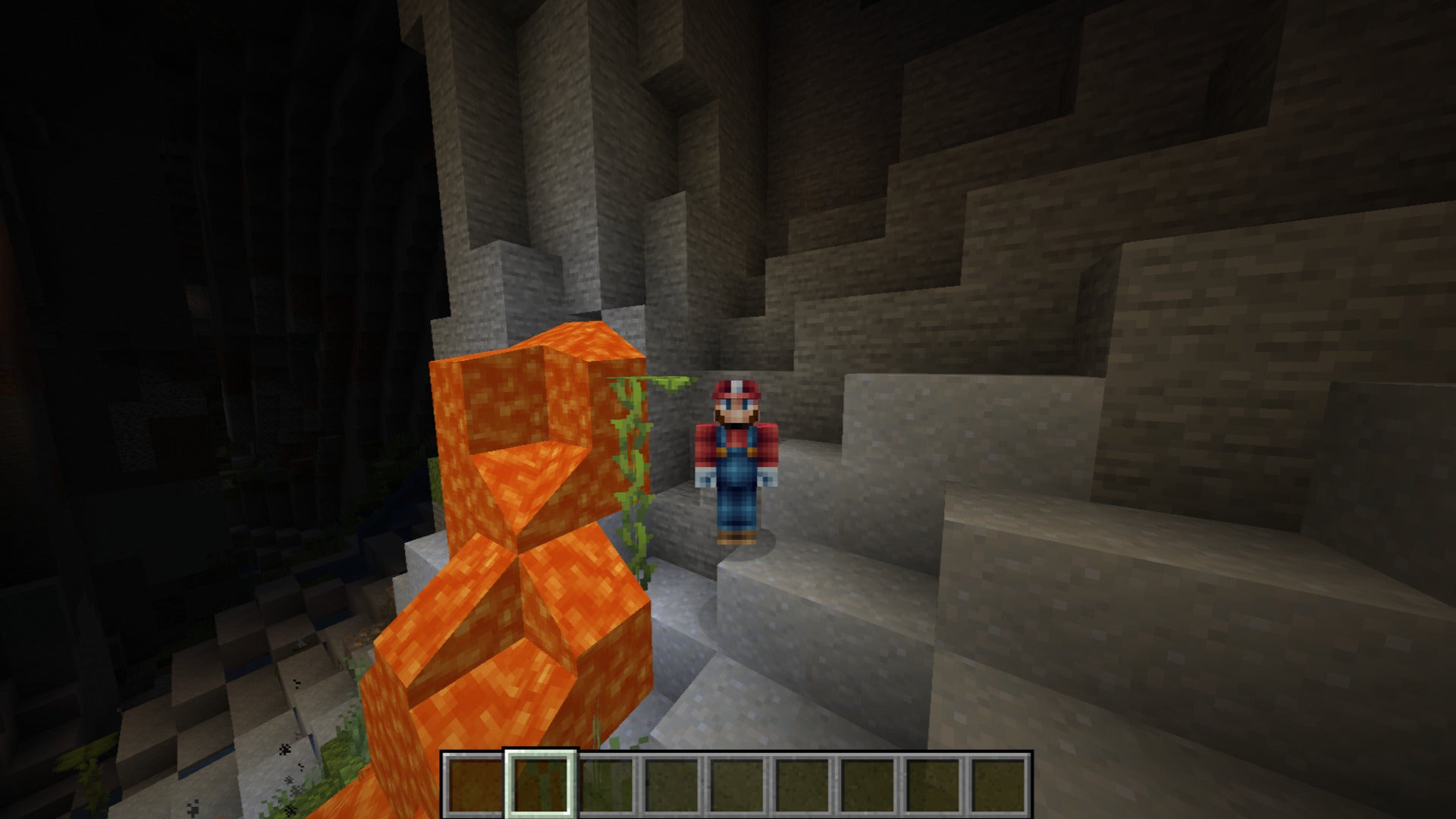 The player, wearing the Mario skin, stands next to some lava in a lush cave in Minecraft