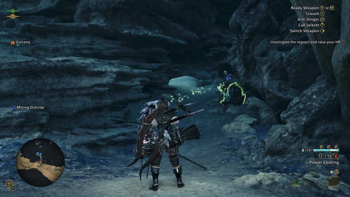 The player character looks at a gap beneath some rocks, beside a mining node, in Monster Hunter Wilds