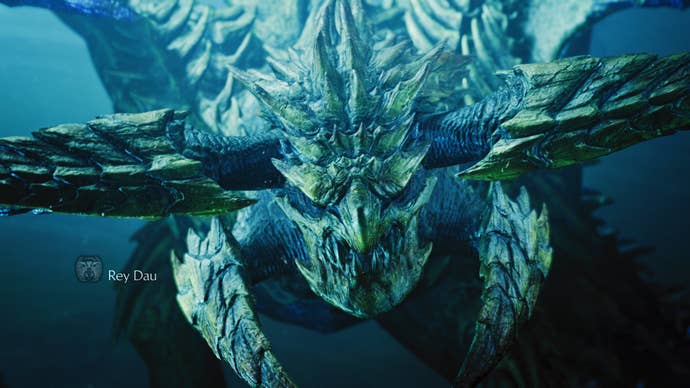 A Monster Hunter Wilds screenshot showing a close-up of the Rey Dau monster wherever you tin spot their yellowish scales and horns astir their face.