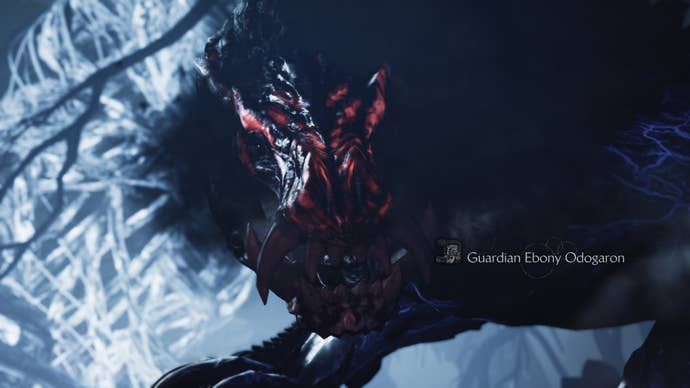 A Monster Hunter Wilds screenshot showing the Guardian Ebony Odogaron’s glowing red face and their large teeth up close.
