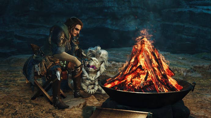 Monster Hunter Wilds screenshot of a hunter and palico sitting next to a fire inside a cave.