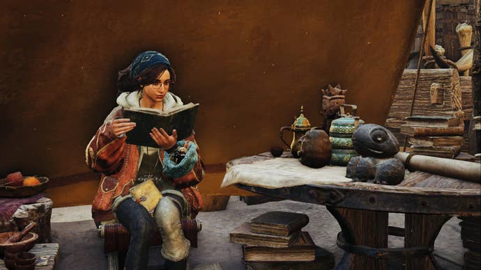 A Monster Hunter Wilds screenshot of Alma reading outside a tent near a table.