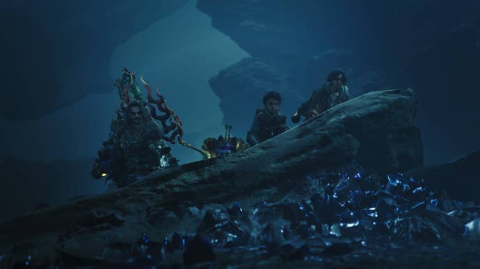 Dark Monster Hunter Wilds screenshot of three people and a palico ducking behind a rock with blue crystal fragments littered along the ground in front of it.