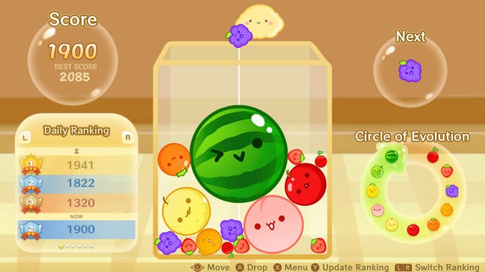 Suika gameplay showing a leaderboard on the left, a guide on the right, and the game area in the middle. A number of different sized round fruits are stacked next to each other. A winking watermelon sits in the middle