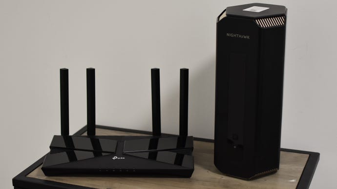 The The Netgear Nighthawk RS700 Wi-Fi 7 router next to a TP-Link Archer AX1500 router, on a small table.
