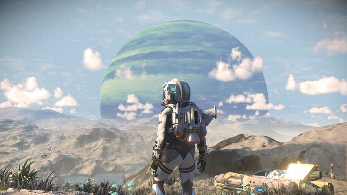 A view of a green gas giant planet through scattered clouds from a rocky planet surface in No Man’s SKy, with a spacesuited character standing in the foreground