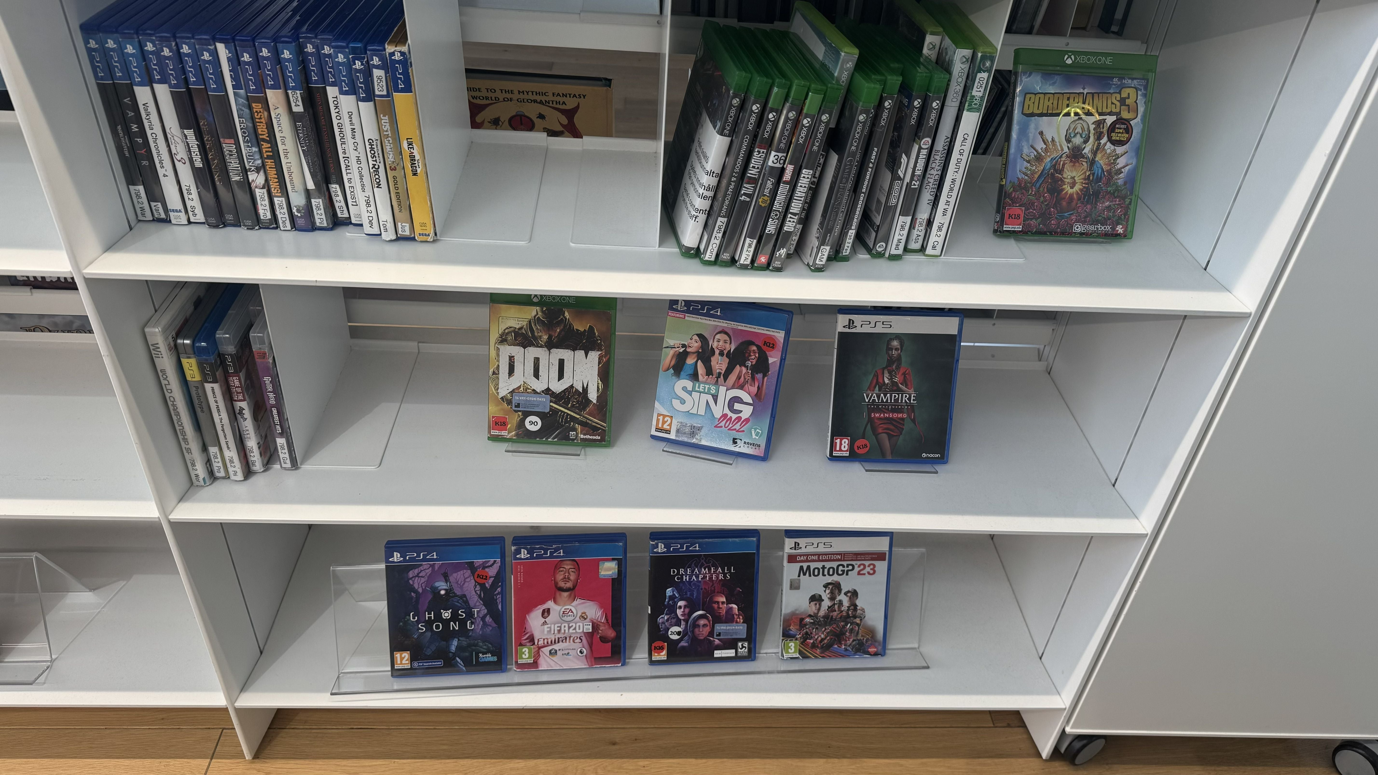 Photo of the Oodi Library in Helsinki showing video games such as Doom 2016 across various platforms on white library shelves