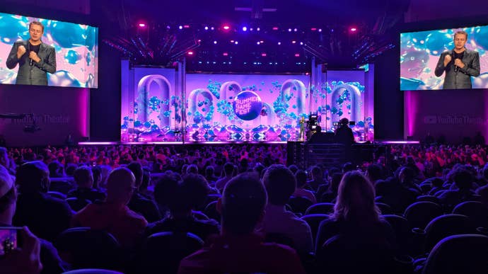 A photograph of Geoff Keighley connected a signifier lit up with swirling animated graphics, from Summer Game Fest 2025's unrecorded showcase.
