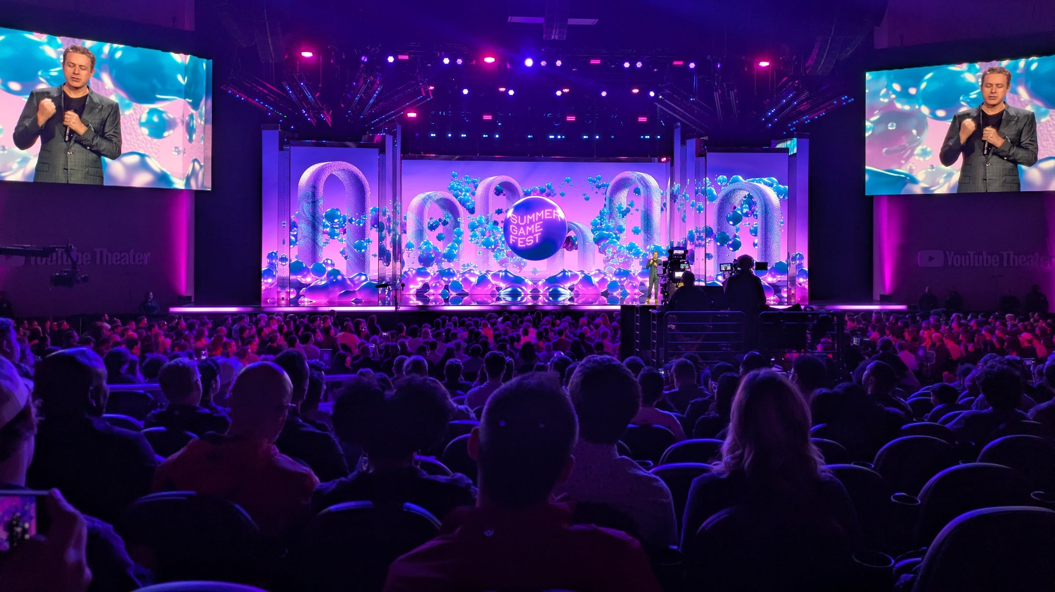 A photograph of Geoff Keighley on a stage lit up with swirling animated graphics, from Summer Game Fest 2025's live showcase. - 1