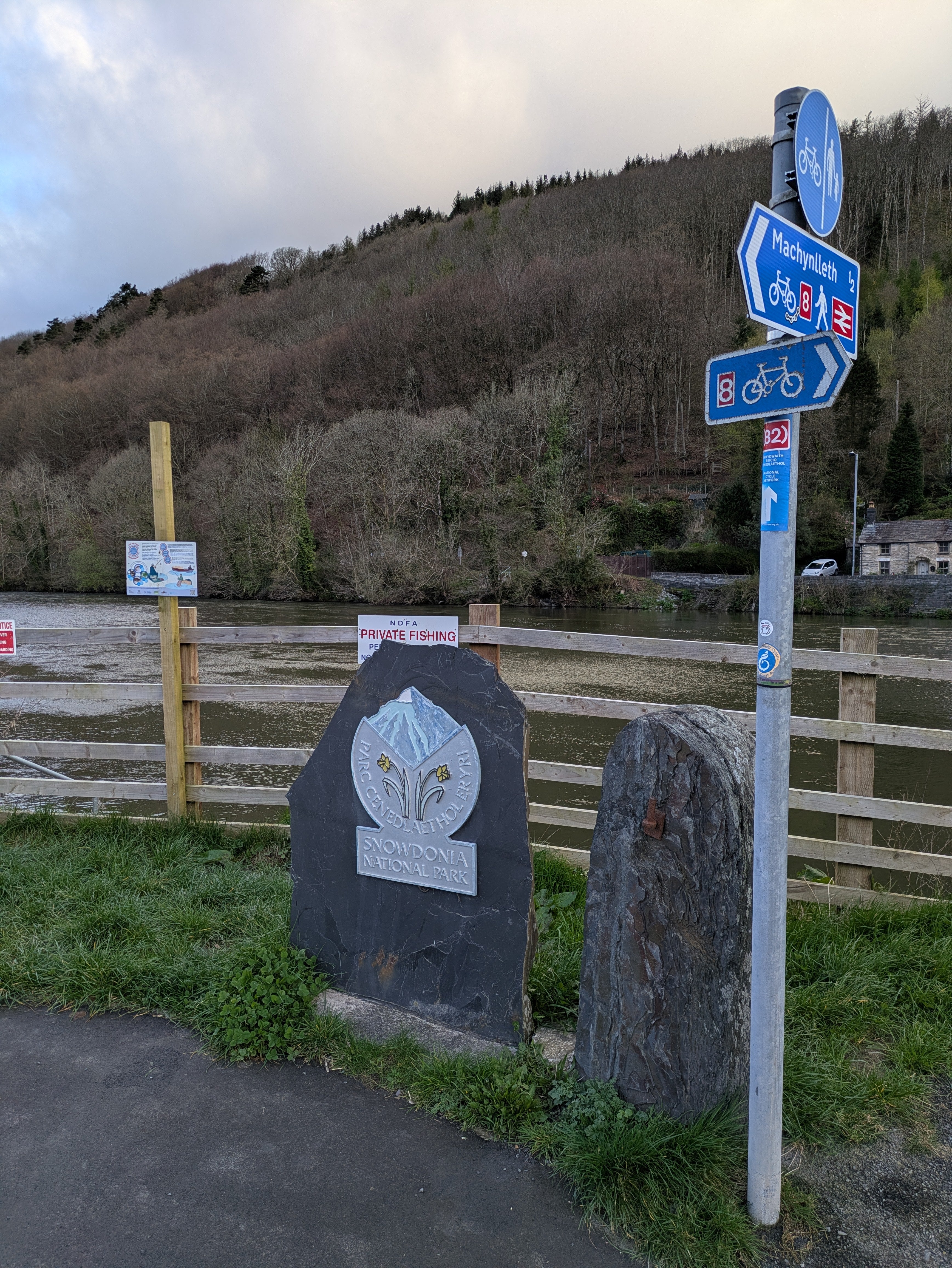 A road sign and an illustrated design on a stone block showing the border of the Snowdonia national park.