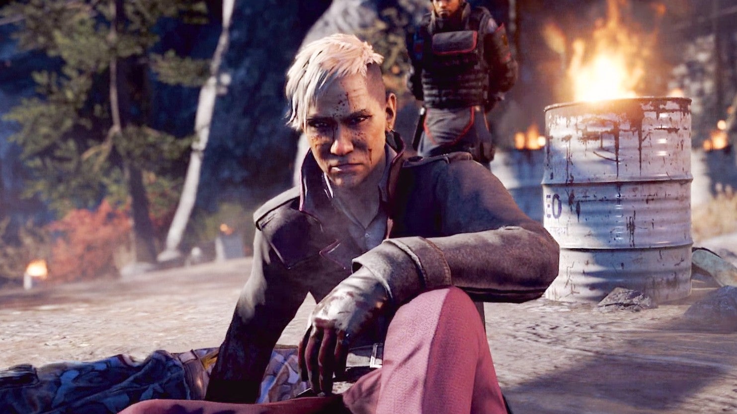 Pagen Min from Far Cry 4 looks disappointed as he sits on the roadside in front of a burning barrel