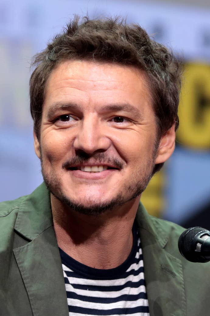 A portrait of Pedro Pascal, smiling handsomely.
