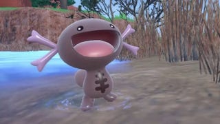 paldean form wooper in a shallow muddy pond with its mouth wide open in a smile