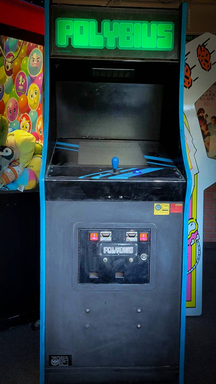 A photograph of a Polybius arcade machine. It is black with blue trim and joysticks and the Polybius name is printed in neon green.