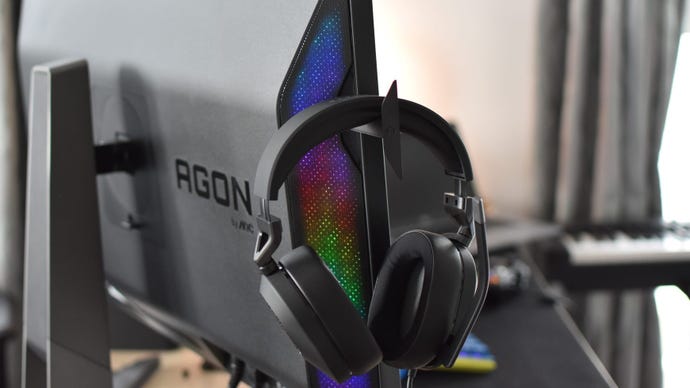 A gaming headset hanging from the hook on the Porsche Design AOC Agon Pro PD32M monitor.