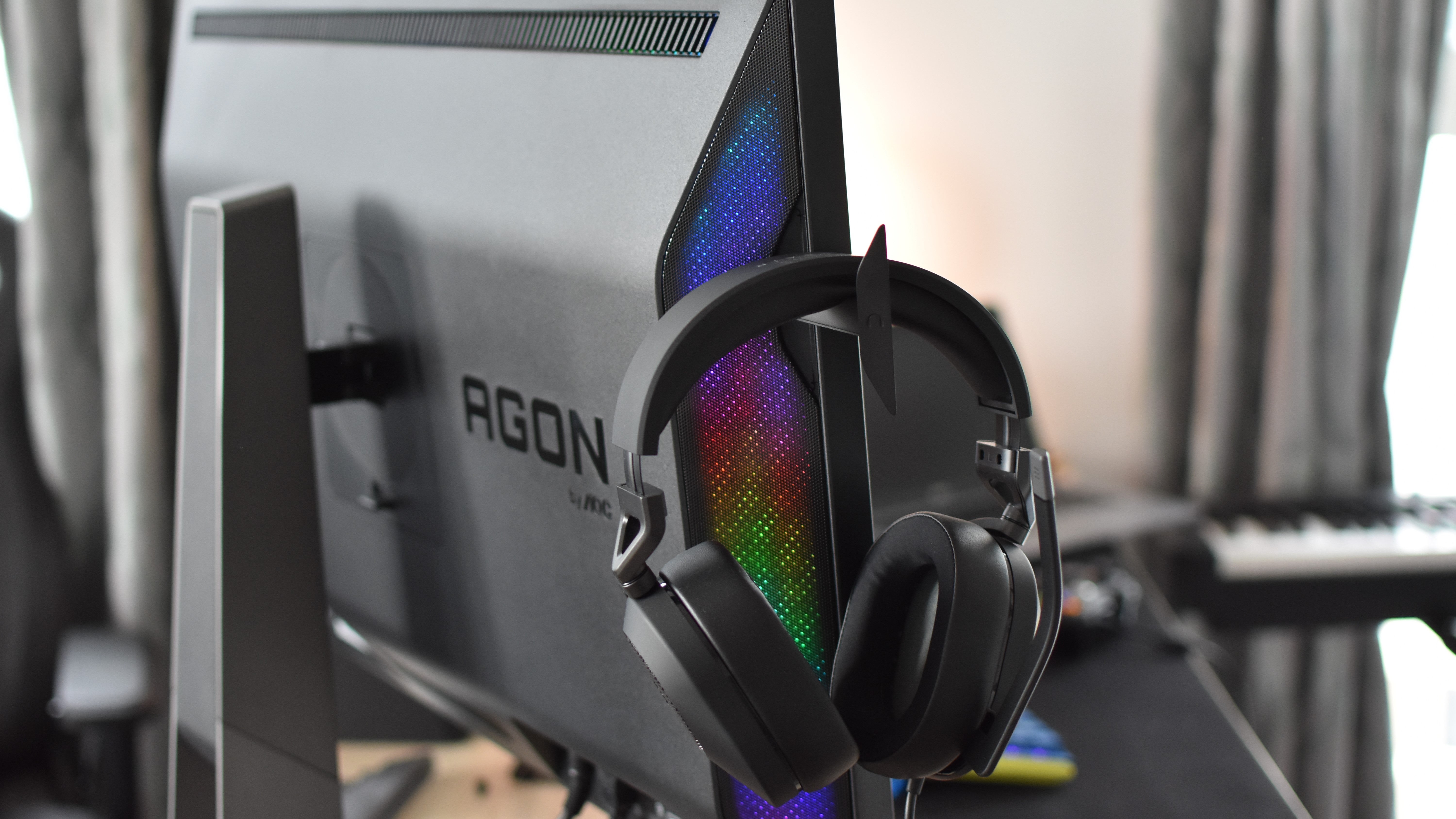 A headset resting on one of the Porsche Design AOC Agon Pro PD32M monitor&rsquo;s pop-out hooks.
