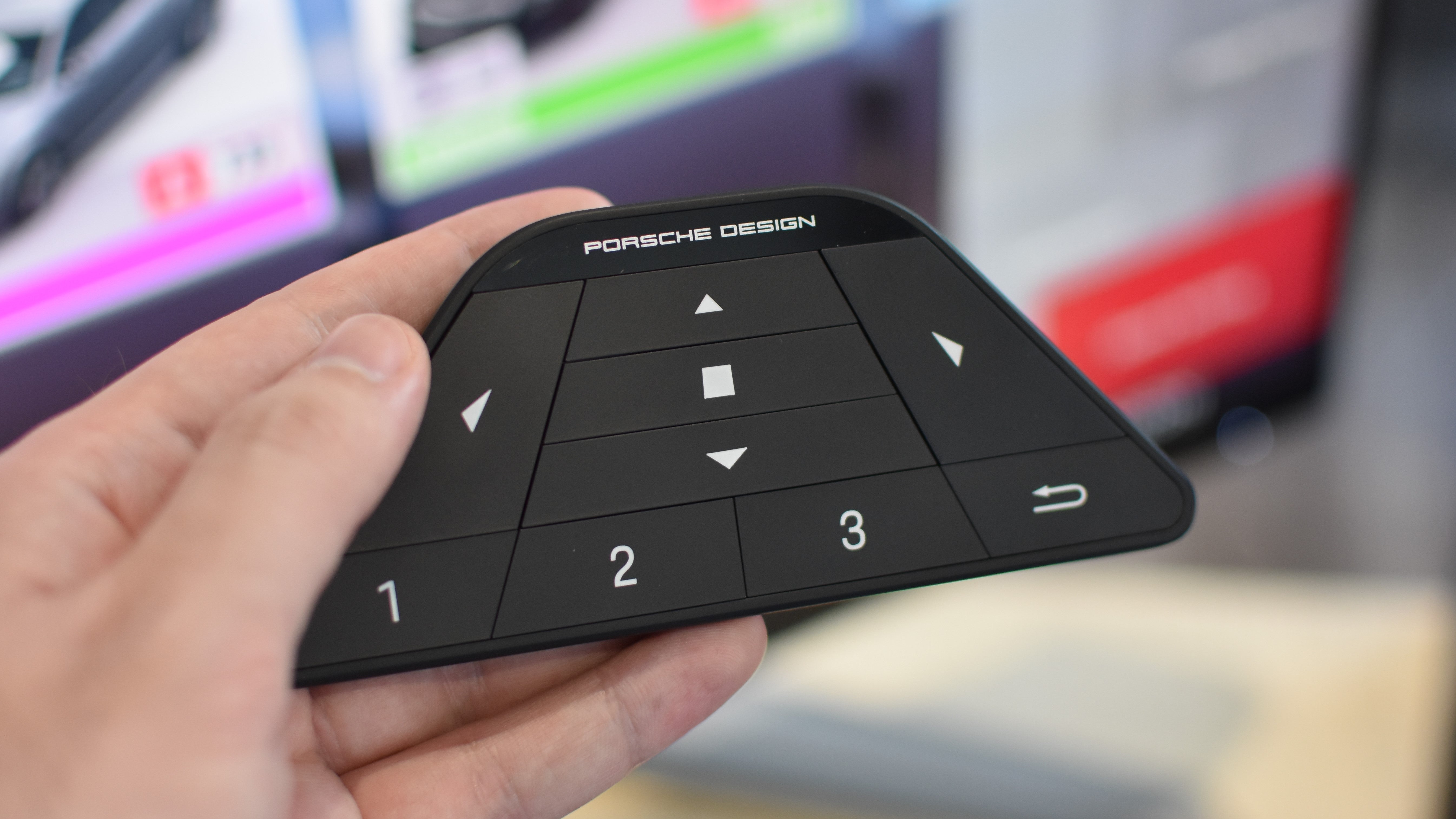 A hand holding the Porsche Design AOC Agon Pro PD32M&rsquo;s remote control.
