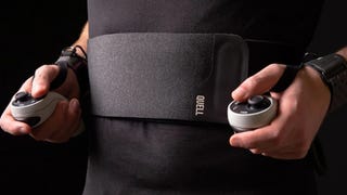 A person is wearing a resistance band on their torso, connected to two game controllers that they're holding in their hands