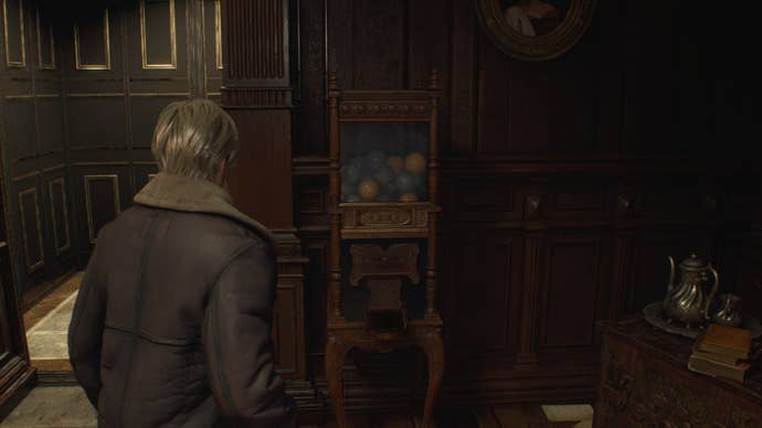 Leon looks at the token/weapon charm vending machine in the firing range in Resident Evil 4 Remake