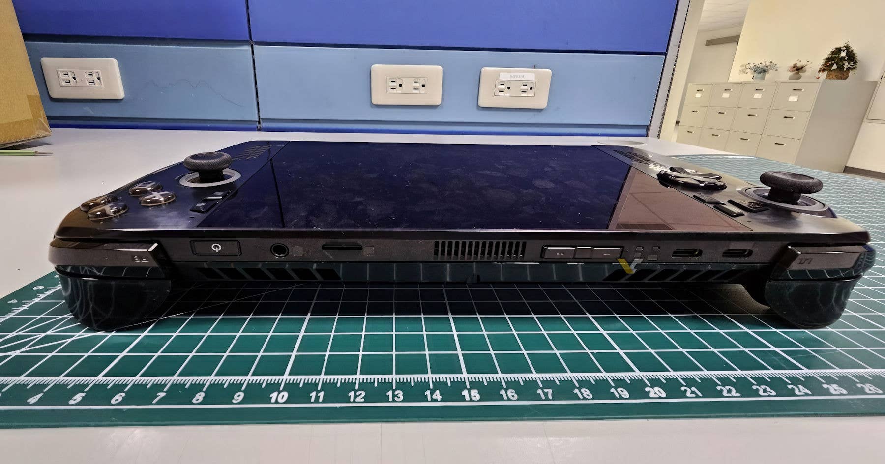 A picture of a test gaming handheld is visible behind an office on a desk