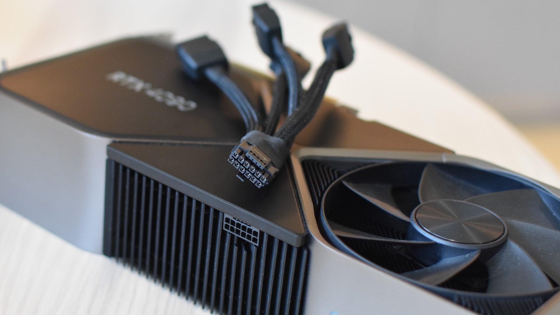 The RTX 4090's power adapter laying on top of an RTX 4090 Founders Edition. - 3