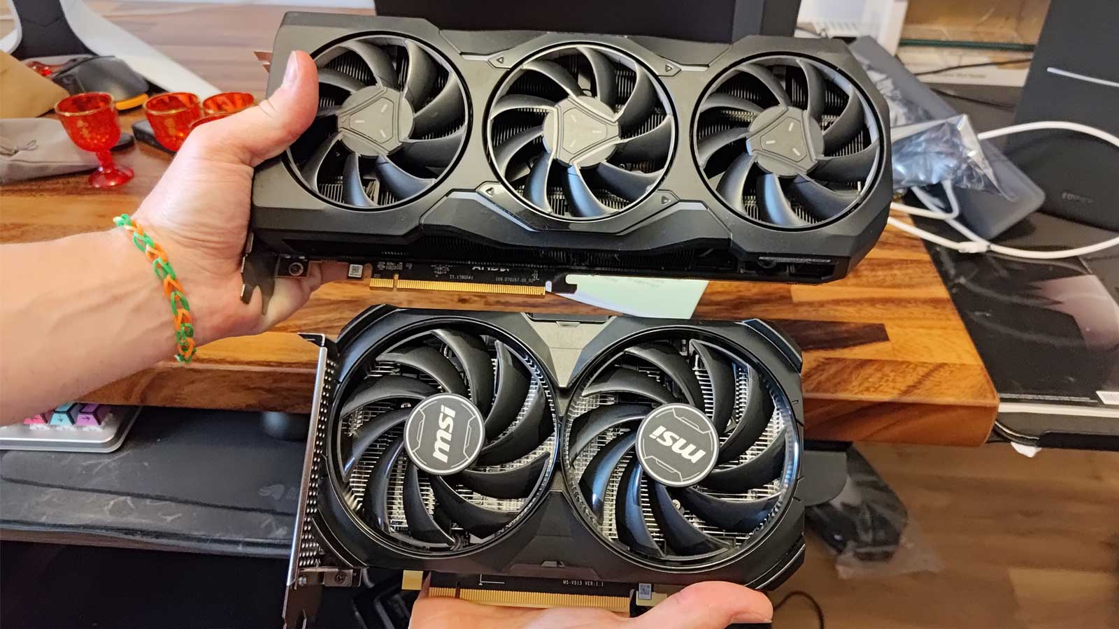 An AMD Radeon 7900 XTX being held next to an Nvidia GeForce RTX 4060 Ti.