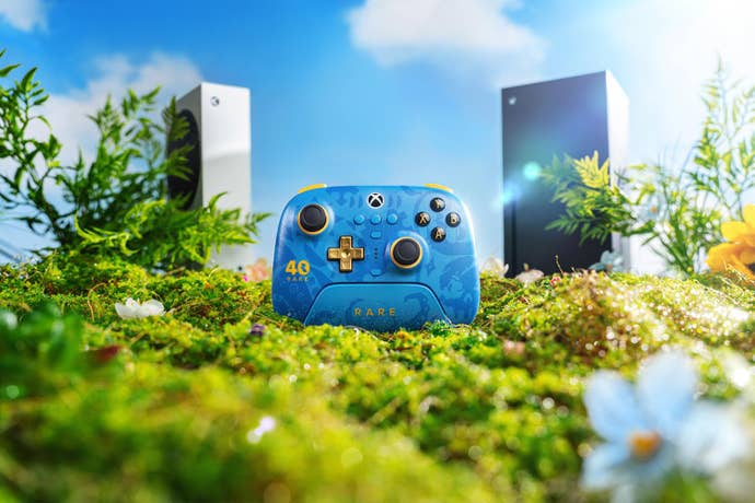 Rare controller on a grassy setting with Xbox's behind it