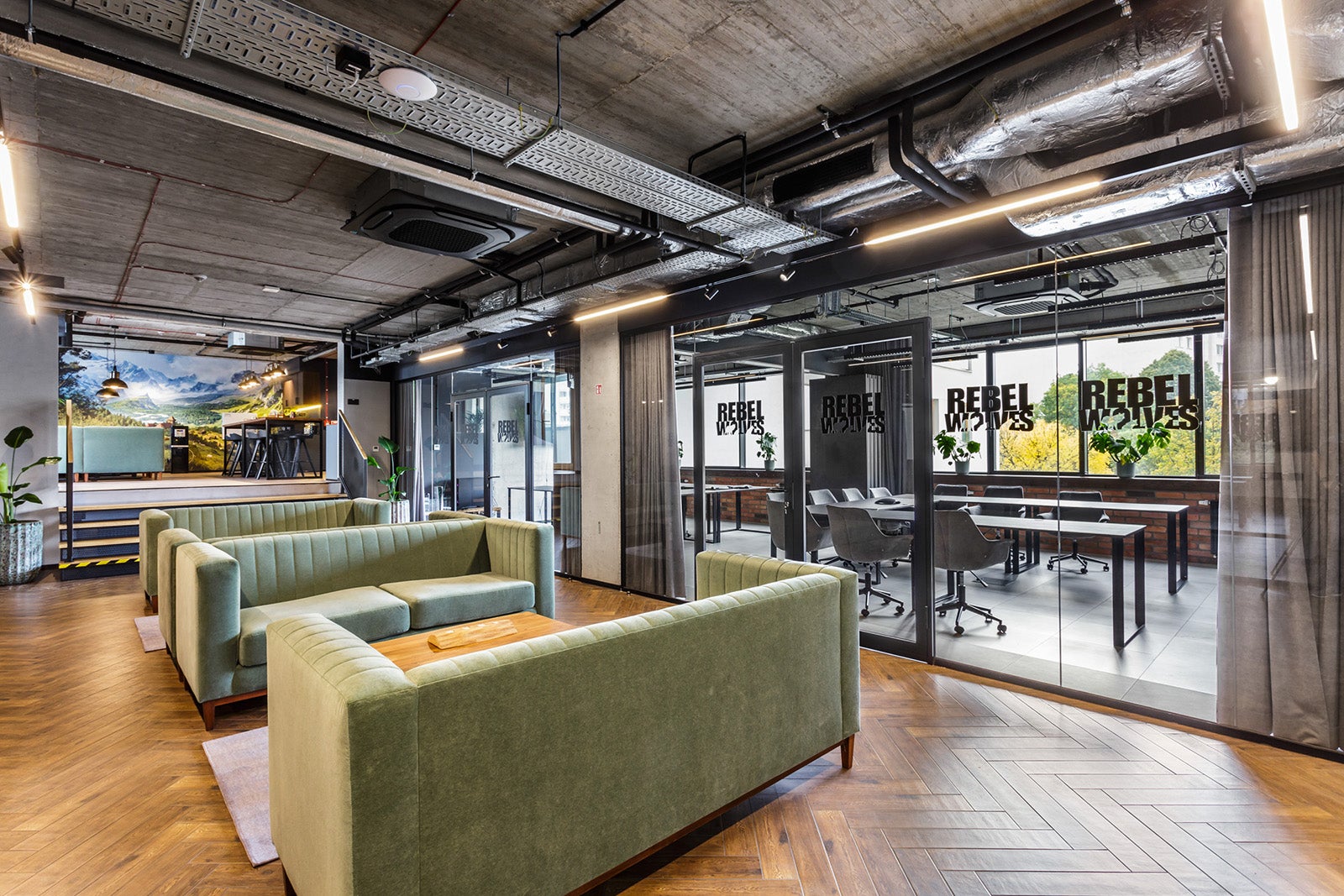 Green sofas and glass walls in the inside of a modern-looking office. It's Rebel Wolves' office in Poland, the developer of The Blood of Dawnwalker.