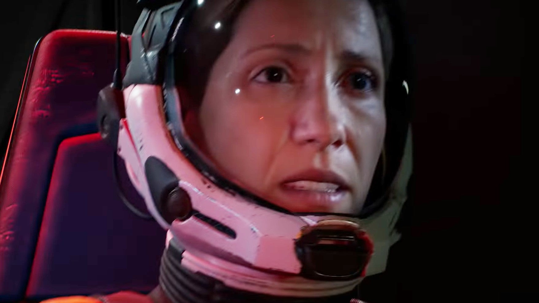 Returnal trailer screenshot showing Selene, a female astronaut, in a space suit and helmet looking concerned as her craft crashes